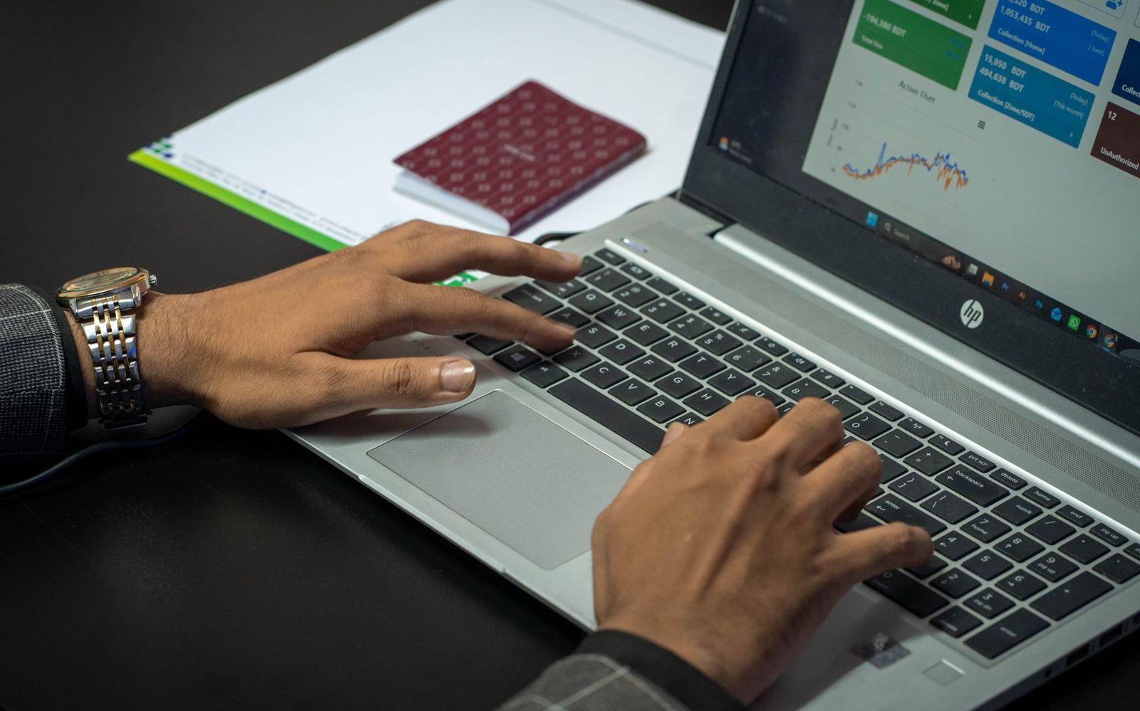 Mãos no teclado de um notebook com painel de dados aberto
