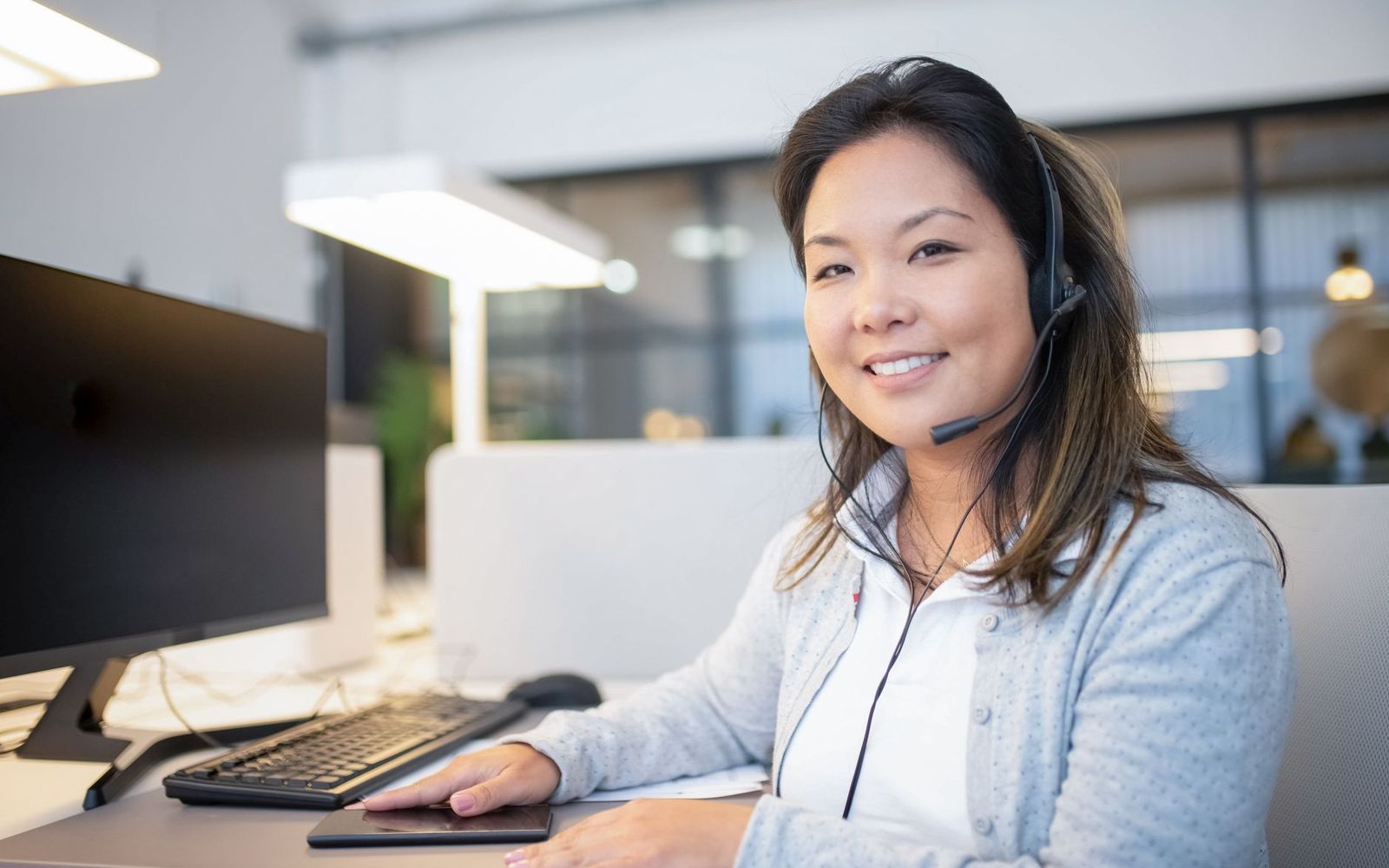 Recepcionista trabalhando ao computador em um balcão de atendimento