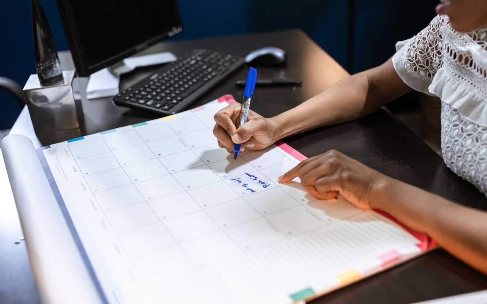Mão anotando compromissos em uma agenda de papel