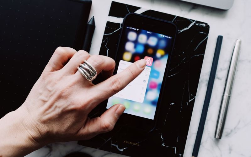 Mãos usando um aplicativo no celular sobre a mesa de trabalho