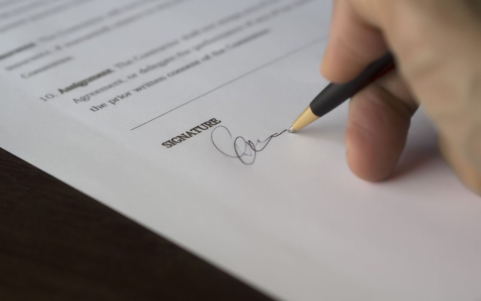 Mão assinando um documento sobre a mesa