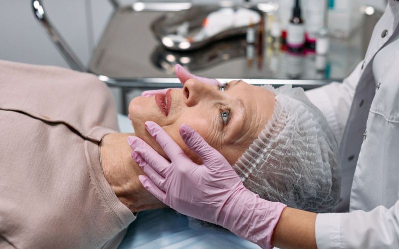 Profissional avaliando o rosto de uma paciente em consultório
